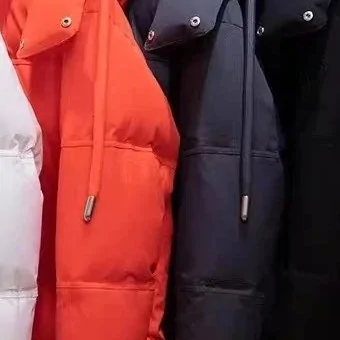 Orange, navy and black hooded puffer jackets hanging side by side on a rail, drawcords loose