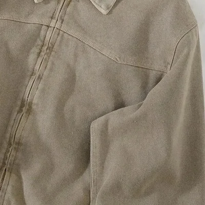 Front of a sand-coloured washed canvas work jacket: centre zip and a curved yoke seam