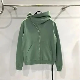 Sage green zip hoodie with an off-centre zip, hanging on a rail against a white wall